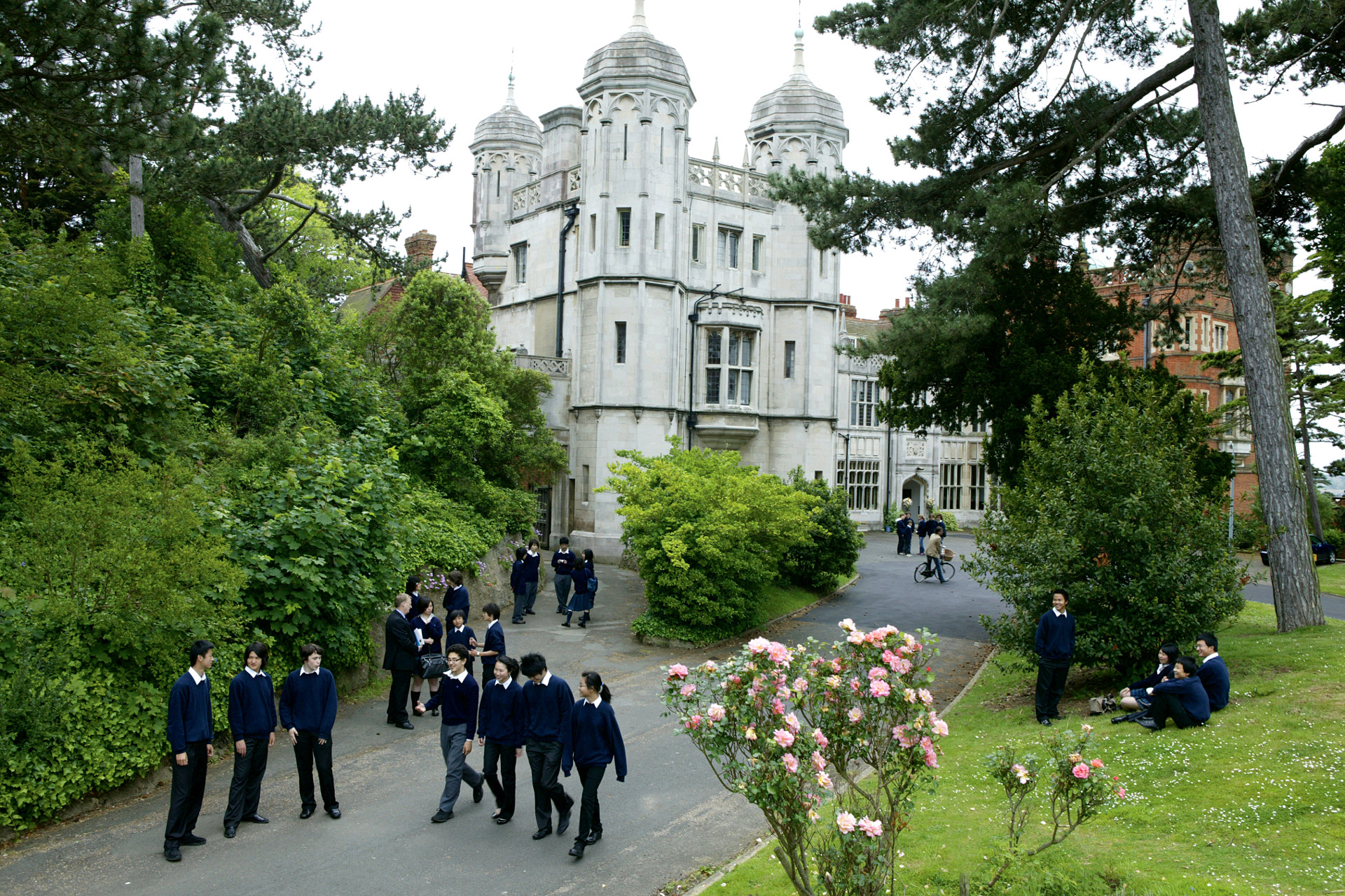 Eine atemberaubende Boarding School in England: historisches Hauptgebäude mit Schülerinnen und Schülern im Park