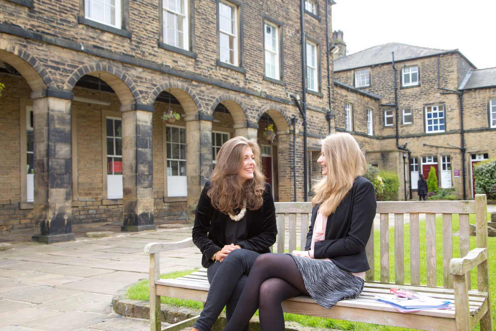 Aufenthalt im Internat – zwei Schülerinnen auf einer Bank im Innenhof einer britischen Boarding School
